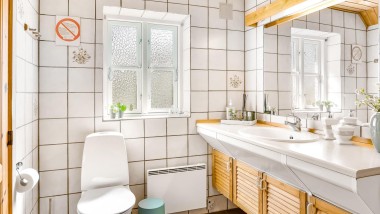 Il bagno originale con WC a pavimento, piastrelle bianche e mobili da bagno in legno (© @triner2 e @strandparken3)