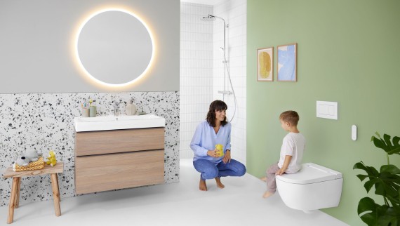 Femme et enfant dans une salle de bains colorée dotée d’un miroir Geberit Option et d’un Geberit AquaClean Alba